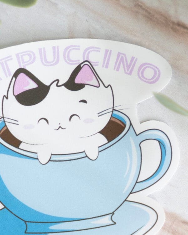 A close up of a sticker with a cat bathing in a cup of coffee with the text catpuccino.