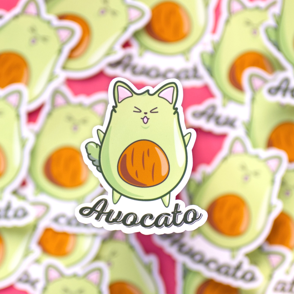 A sticker of a happy green avocado shaped like a cat with the text avocato below.