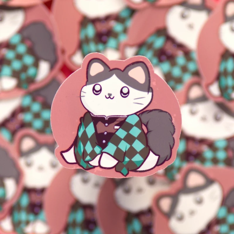 A round sticker of a cat in a green-black checkered coat. Inspired by Tanjuro from the manga Demon Slayer.