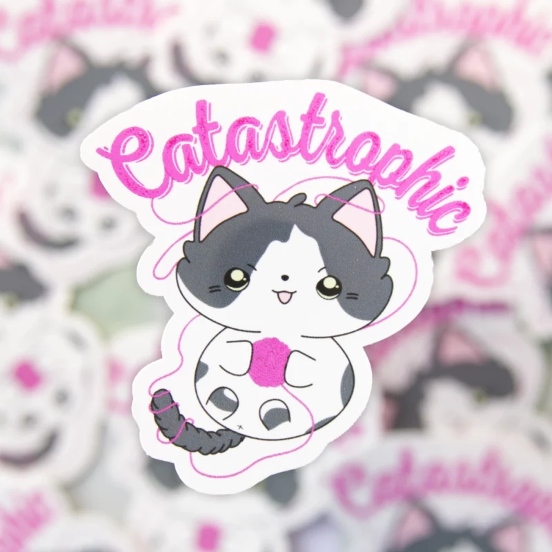 A sticker of a cat playing with a yarn ball with the text catastrophic above it.