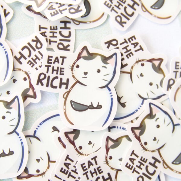 Several stickers of a cat holding a knife with the text eat the rich.