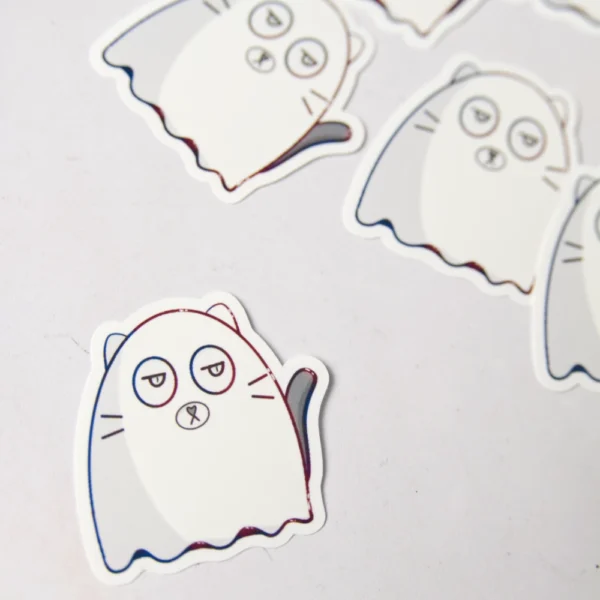 several cat ghost stickers are scattered on the ground. the ghost is white