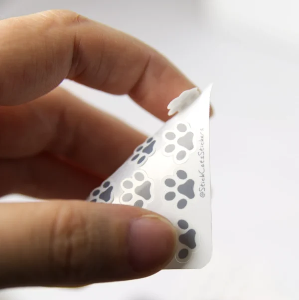 A hand is peeling off a sticker on a mini paw sticker sheet.