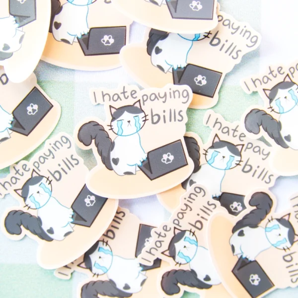 Several stickers of a cat crying in front of a computer with the words I hate paying bills over.