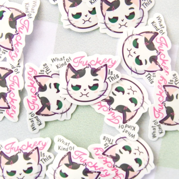 Several stickers laying of a cat not looking content with the words what kind of fuckery is this.