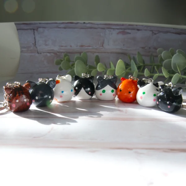 A row of keychains made from polymer clay. The keychains are shaped like cats in various colors.